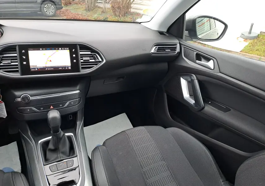 Intérieur noir de la Peugeot 308 2019, vue côté passager sur tableau de bord et console centrale avec écran tactile.