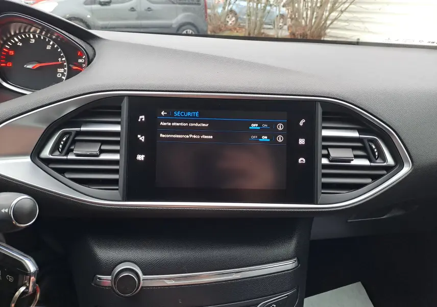 Vue rapprochée du tableau de bord noir de la Peugeot 308 2019 avec écran tactile affichant les options de sécurité.