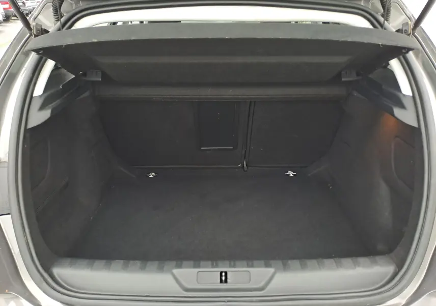 Coffre ouvert d'une Peugeot 308 gris, vue de l'arrière montrant un espace de chargement vide et propre.