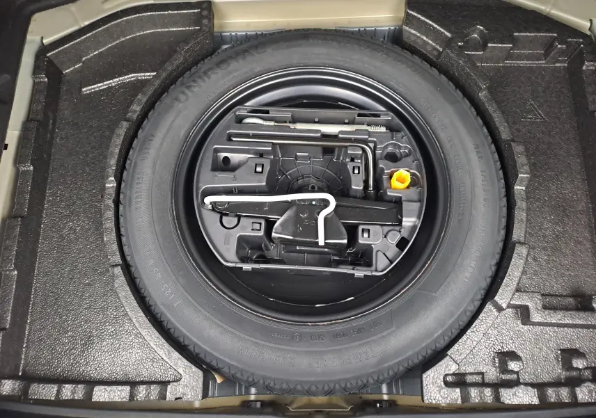 Gros plan sur la roue de secours et les outils de bord dans le coffre d'une Peugeot 308 gris 2019.