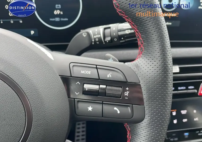 Gros plan sur le volant sport en cuir noir avec surpiqûres rouges du Hyundai Tucson 2025, affichage digital en arrière-plan.