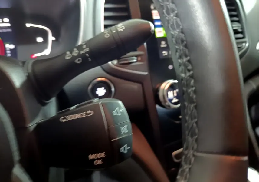 Gros plan sur le volant multifonctions noir de la Renault Mégane Business Blue dCi 115, avec commandes audio visibles.