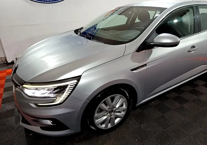 Vue 3/4 avant droit d'une Renault Mégane Business Blue dCi 115 EDC gris clair avec feux LED allumés.