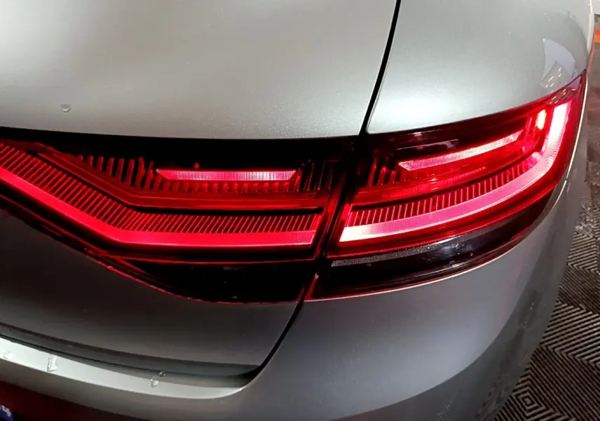 Gros plan sur le feu arrière droit rouge d’une Renault Mégane Business gris clair, vue en léger angle arrière.