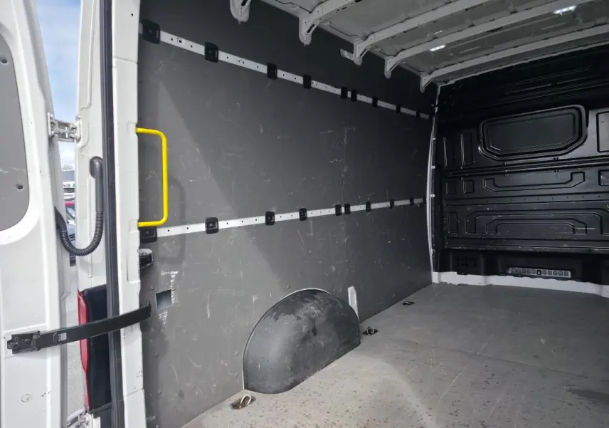 Vue intérieure de l'espace de chargement du Volkswagen Crafter blanc, avec plancher bois et parois grises.