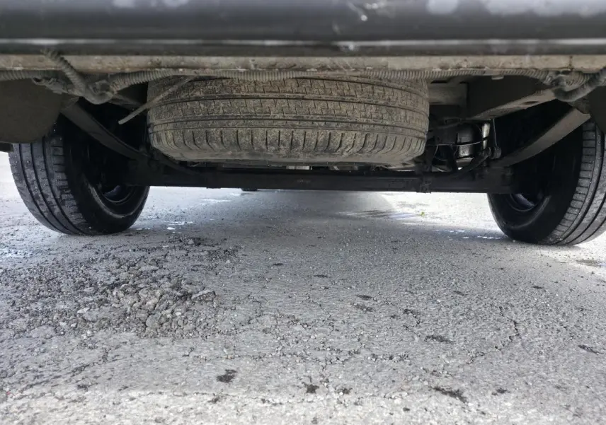Vue en contre-plongée sous un Volkswagen Crafter blanc, montrant la roue de secours et l'essieu arrière.