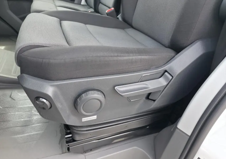 Gros plan sur le siège conducteur gris foncé du Volkswagen Crafter Fourgon 2023, avec commandes manuelles de réglage visibles.