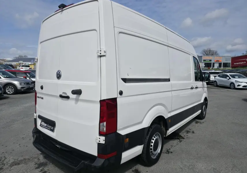 Vue 3/4 arrière droite d'un Volkswagen Crafter blanc avec portes battantes arrière et protections latérales noires.