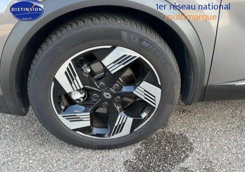 Gros plan sur la roue avant droite noire et argentée d'une Renault Symbioz grise, avec logo Renault au centre.