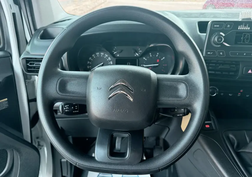 Vue intérieure centrée sur le volant noir du Citroën Berlingo blanc 2019, avec tableau de bord et console visibles.