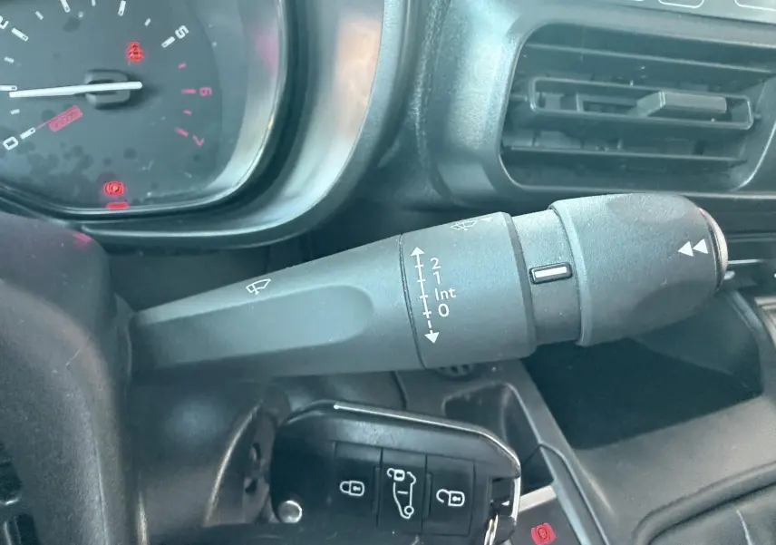 Gros plan sur la commande d’essuie-glace et le tableau de bord intérieur du Citroën Berlingo 2019 blanc.