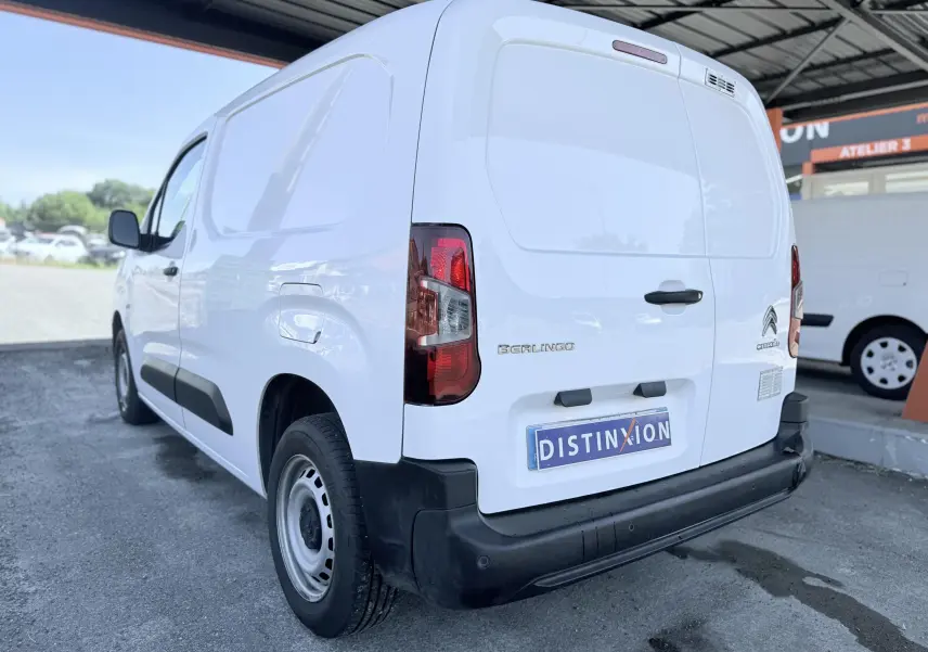 Vue 3/4 arrière droite d’un utilitaire Citroën Berlingo blanc avec pare-chocs noir et plaque Distinxion.