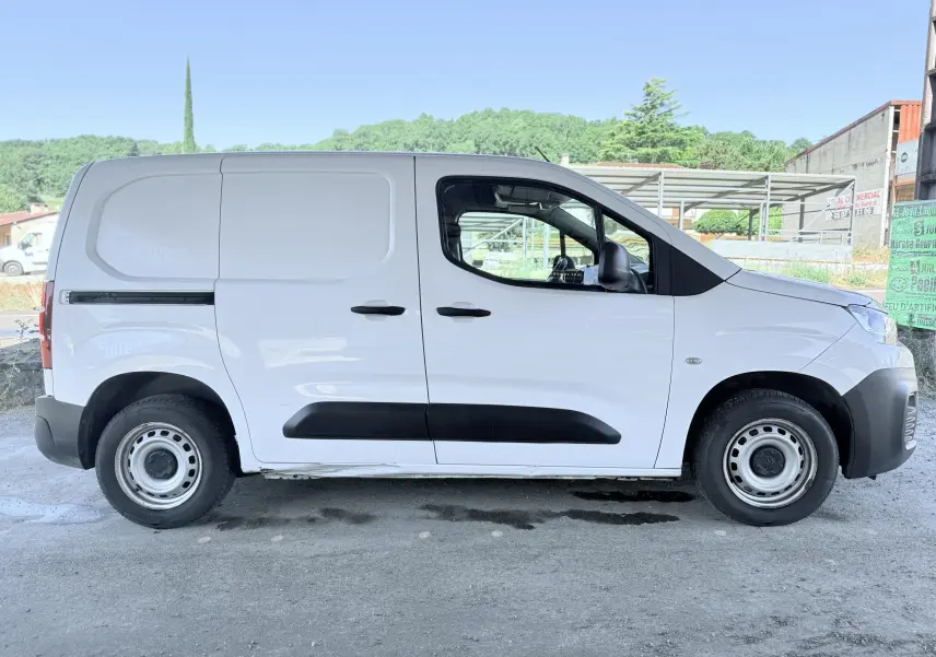 Vue de profil côté gauche d’un utilitaire Citroën Berlingo blanc avec protections noires et jantes acier.