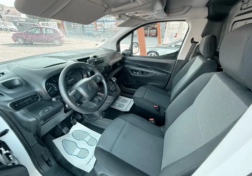 Vue intérieure côté conducteur du Citroën Berlingo blanc 2019, montrant le tableau de bord et les sièges tissu gris.