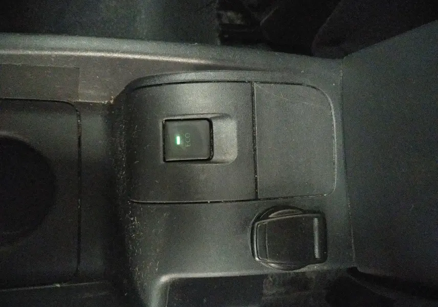 Gros plan sur le bouton ECO activé et prise 12V dans la console centrale noire du Renault Kangoo blanc 2019.