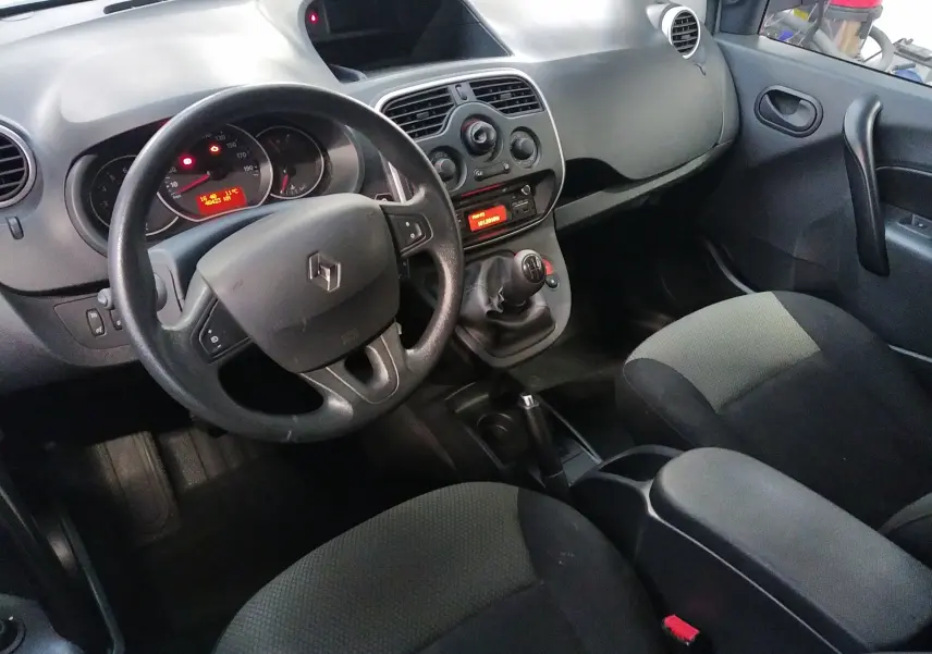 Vue intérieure côté conducteur du Renault Kangoo blanc 2019, volant multifonction et console centrale avec boîte manuelle.
