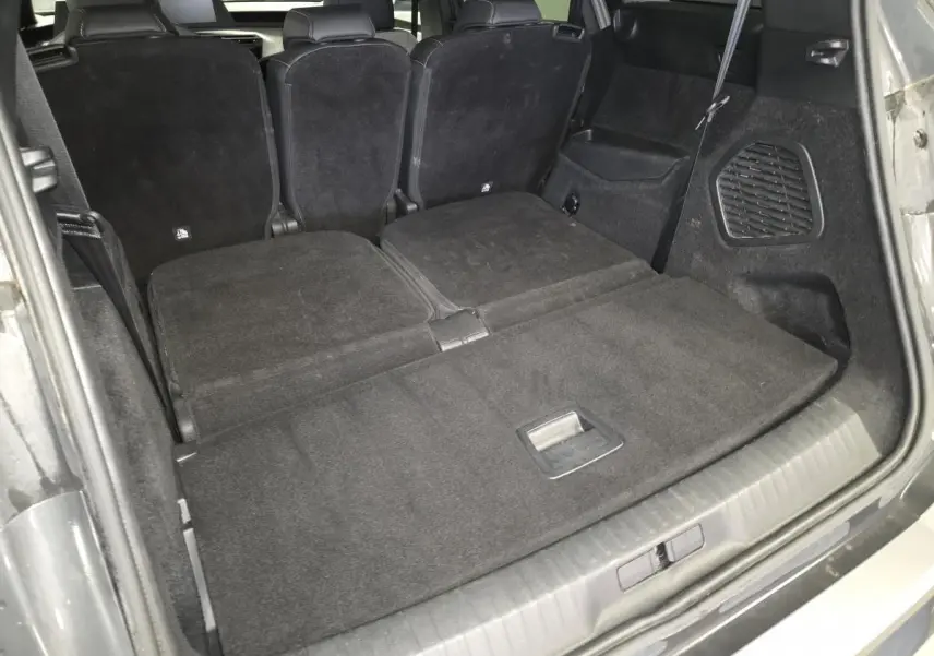 Coffre ouvert du Peugeot 5008 gris, sièges arrière rabattus offrant un espace de chargement plat et spacieux.