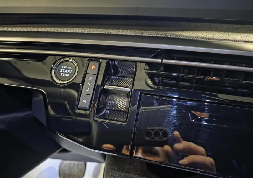 Détail de la console centrale noire laquée avec bouton start/stop et sélecteur de boîte auto du Peugeot 5008 gris hybride 2025.