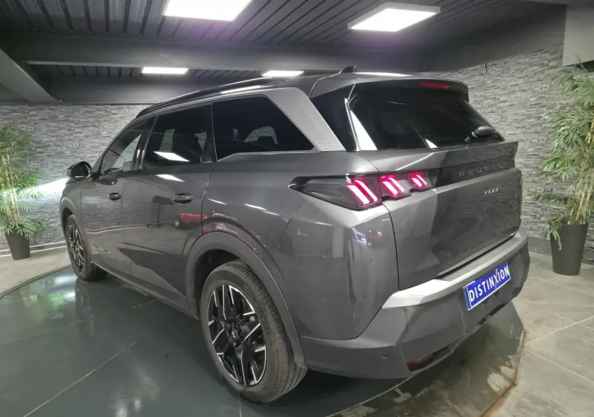 Vue 3/4 arrière droite d'un Peugeot 5008 gris métallisé avec feux arrière à LED en forme de griffes et jantes alliage noires.