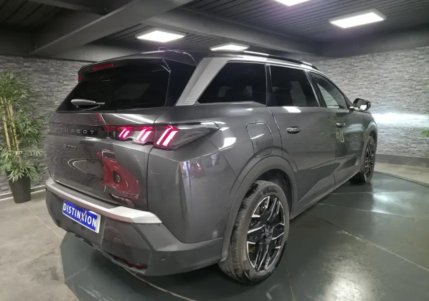 Vue 3/4 arrière droite d’un Peugeot 5008 gris métallisé avec feux arrière LED 3 griffes et jantes alliage noires.