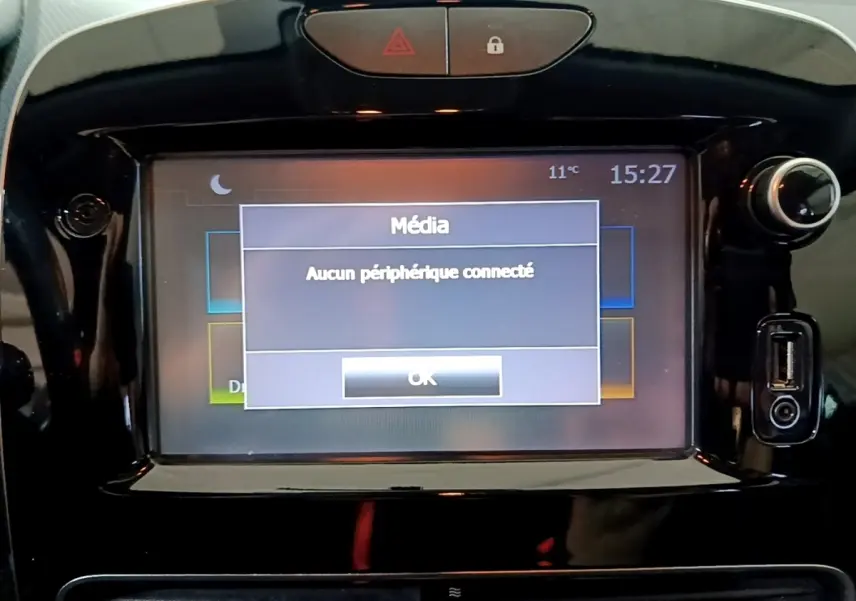 Vue rapprochée de l’écran tactile central noir brillant de la Renault Clio Business gris clair affichant un message média.