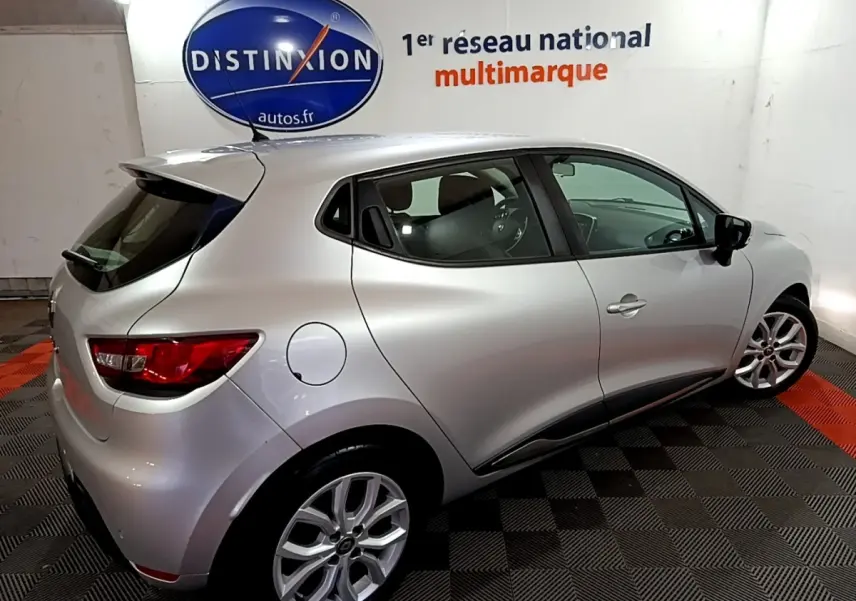 Vue 3/4 arrière droite d'une Renault Clio Business gris clair 2018 dans un showroom avec logo Distinxion en arrière-plan.