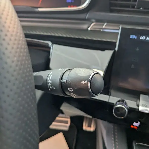 Gros plan sur la commande d'essuie-glace à gauche du volant dans l'habitacle gris noir du Peugeot 508 SW 2024.