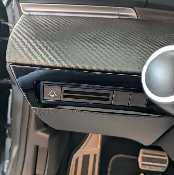 Détail du tableau de bord côté conducteur du Peugeot 508 SW gris Selenium 2024 avec texture carbone et commande d'aide à la conduite.