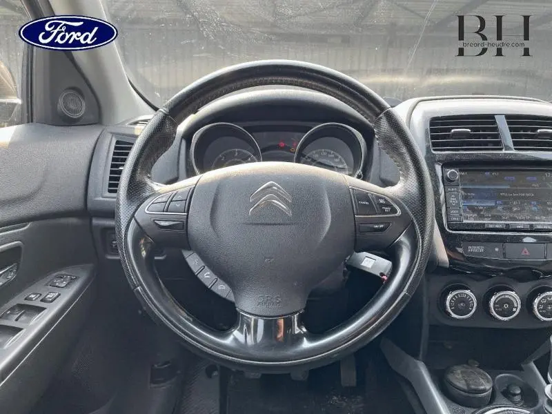 Vue intérieure centrée sur le volant cuir noir du Citroën C4 Aircross 2016 avec tableau de bord et écran tactile visible