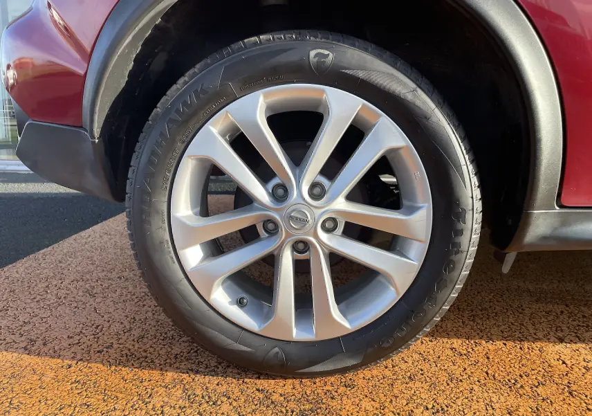 Gros plan sur la roue avant gauche du Nissan Juke rouge 2017, mettant en valeur la jante alliage 17 pouces et le pneu Firehawk.