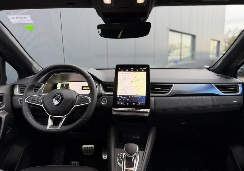 Vue intérieure frontale du tableau de bord du Renault Captur Bleu Iron avec écran tactile vertical et volant multifonction.