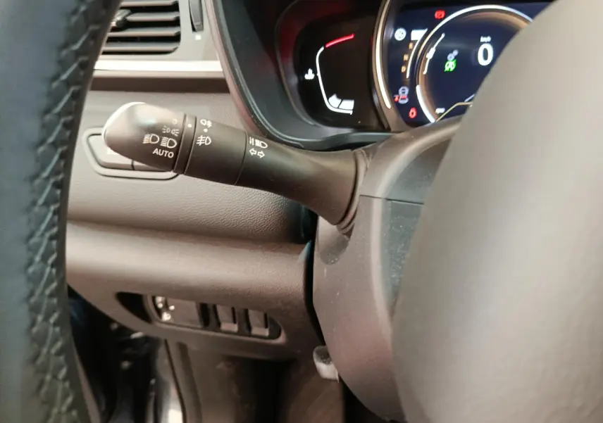 Gros plan sur la manette de commandes d'éclairage à gauche du volant dans le tableau de bord du Renault Kadjar Business gris foncé.