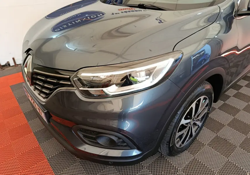 Vue 3/4 avant droit du Renault Kadjar Business gris foncé, mettant en valeur le phare LED et la calandre distinctive.