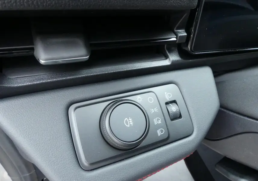 Gros plan sur la commande des phares du Ford Puma 2025, avec finition intérieure noire et surpiqûres rouges visibles.