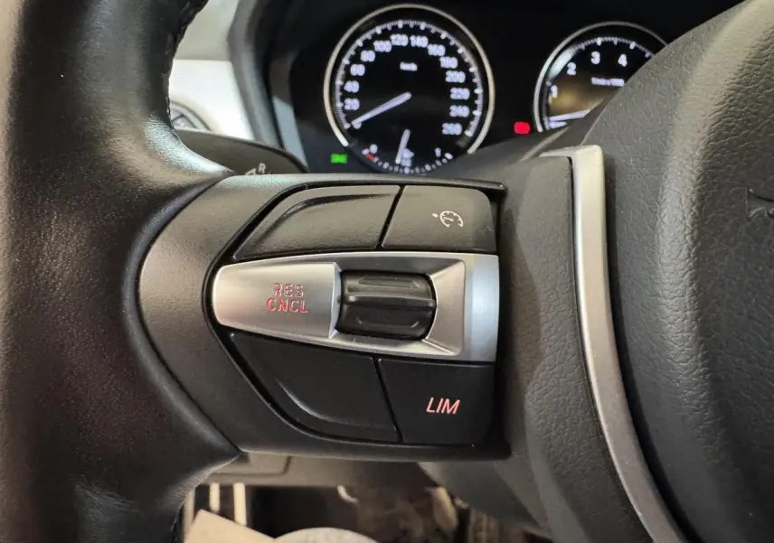 Gros plan sur les commandes du régulateur de vitesse au volant cuir d’une BMW X2 xDrive25e M Sport 2021.