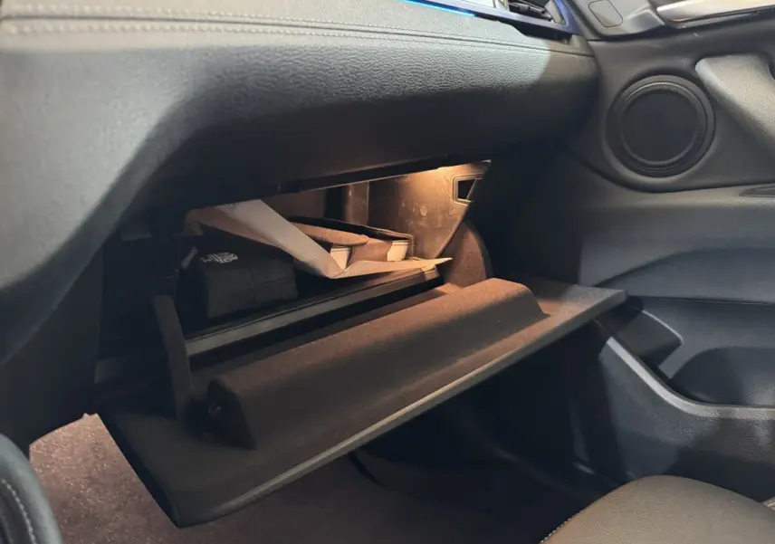 Vue intérieure sur la boîte à gants ouverte du BMW X2 xDrive25e M Sport 2021, avec éclairage intérieur et rangements visibles.