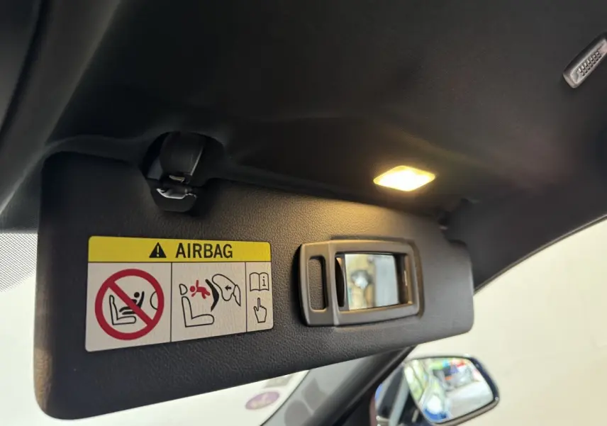 Détail du pare-soleil côté conducteur avec miroir et avertissement airbag dans un BMW X2 bleu 2021.