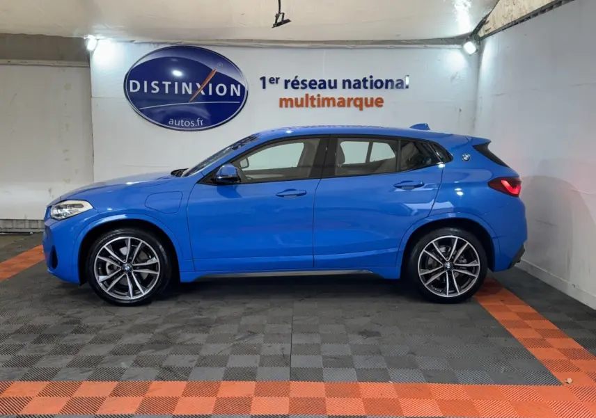 BMW X2 xDrive25e M Sport bleu, vue de profil côté gauche, avec jantes alliage et logo BMW sur l'aile arrière.