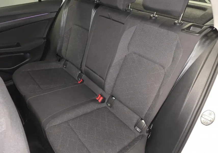 Vue intérieure côté droit de la banquette arrière tissu gris foncé de la Volkswagen Golf VIII blanche, avec ceintures de sécurité visibles.