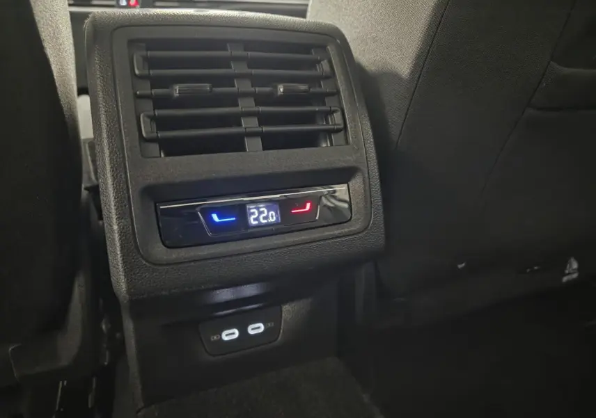 Détail de la console arrière noire avec ventilation et affichage digital de la climatisation à 22°C sur Volkswagen Golf VIII blanche.