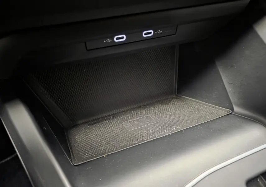 Gros plan sur la zone de recharge sans fil et deux ports USB-C éclairés dans la console centrale d'une Volkswagen Golf VIII blanche.