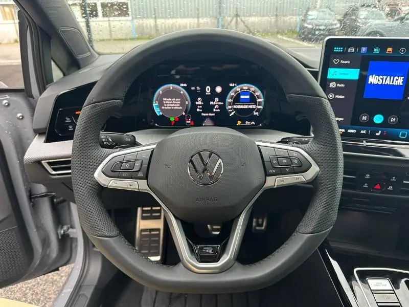 Vue frontale du volant cuir noir et multifonction de la Volkswagen Golf gris Urano avec tableau de bord numérique et écran tactile.