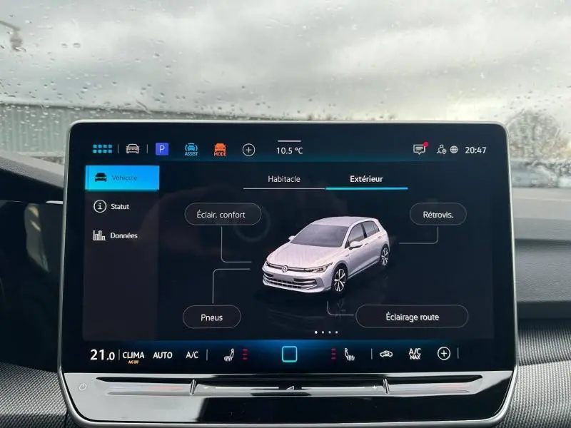 Écran tactile intérieur affichant une vue 3/4 avant d'une Volkswagen Golf gris clair sur interface de contrôle véhicule.