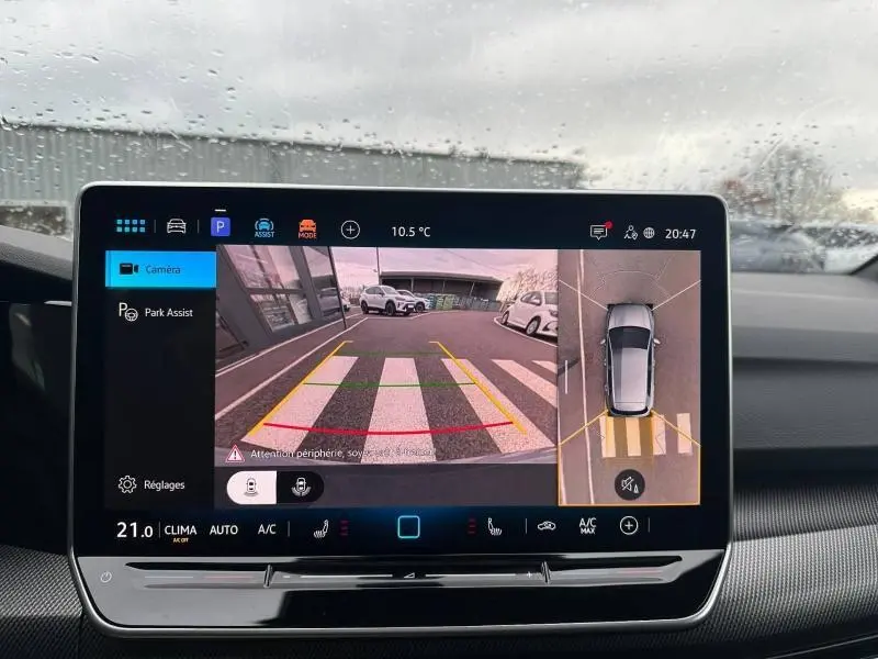 Écran tactile intérieur montrant la caméra de recul et la vue 360° d'une Volkswagen Golf gris Urano en stationnement.
