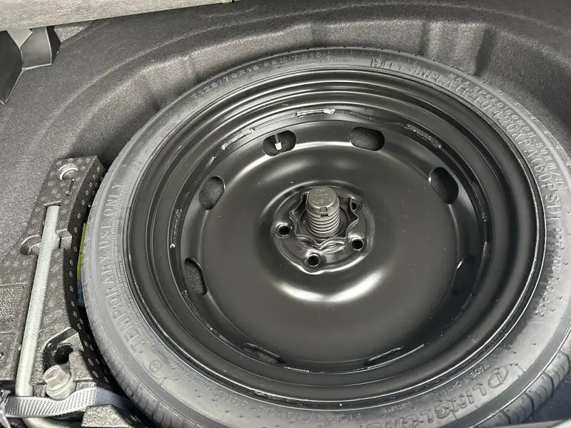 Vue rapprochée de la roue de secours noire dans le coffre d'une Volkswagen Golf 2.0 TDI gris Urano 2026.