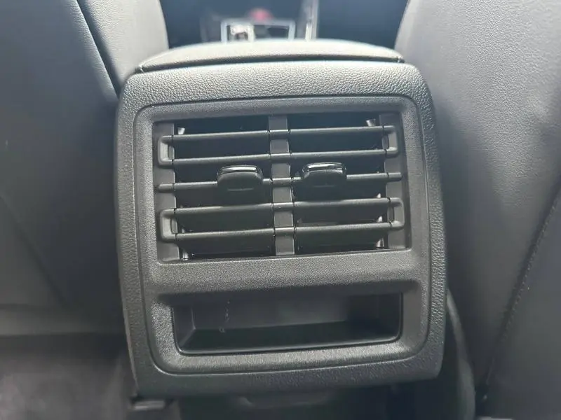 Grille d'aération arrière noire vue de face entre les sièges avant d'une Volkswagen Golf gris Urano 2026.