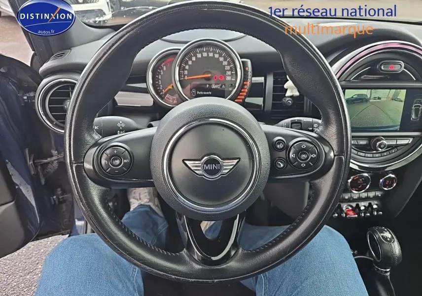 Vue centrée sur le volant cuir multifonction d'une MINI Cooper S bleu nuit, avec tableau de bord et écran multimédia visibles.