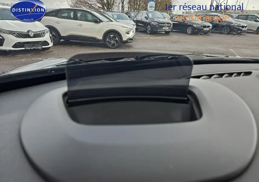 Vue intérieure du tableau de bord de la MINI Cooper S 2015 avec écran tête haute déployé, arrière-plan extérieur flou.