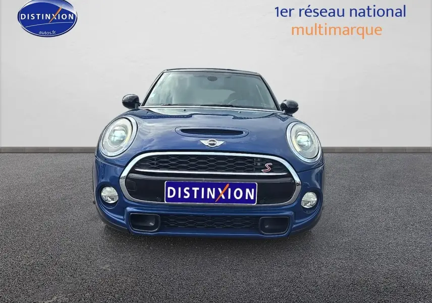 Vue frontale d'une MINI Cooper S bleu nuit avec calandre noire et détails chromés, phares ronds allumés.