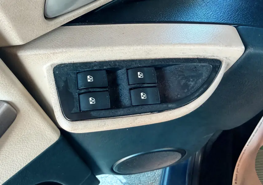 Gros plan sur les commandes des vitres électriques sur la portière avant gauche d'une Renault Avantime gris de 2002.